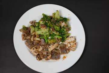 sauteed mushrooms with garlic and parsley on a black plate on white background 