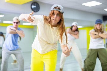 Teen girl in cap rehearses hip hop dances in dance hall