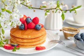 Pancakes served on a white plate with fresh fruit