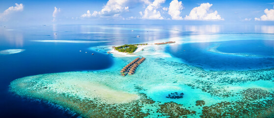 Panoramic aerial view of a turquoise coral reef and lagoon with a tropical paradise island and calm...