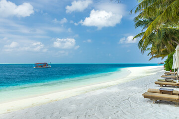 white sandy shoreline in the Maldives; boat in the water