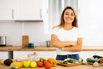 Portrait of pleased housewife preparing salad in modern kitchen