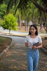 Young woman checking plants in the park with tablet.