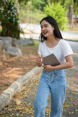 Young woman checking plants in the park with tablet. She was laughing happily at the work she did.