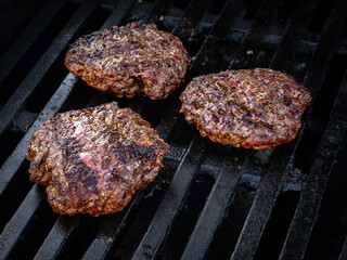 Three homemade hamburgers on the barbeque grill.