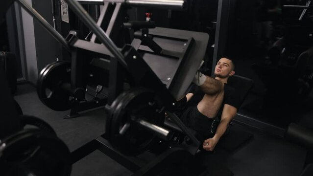 Fitness instructor, Sportsman uses, Healthy lifestyle. Sportsman uses leg exercise machine to develop muscle mass.