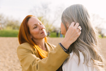 An adult daughter strokes the hair of an elderly gray-haired mother. The concept of caring for an elderly mother and intergenerational relationships