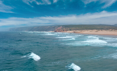 Summer Atlantic coast and sandy beach Praia da Bordeira. Misty view (Carrapateira, Algarve, Portugal).  People unrecognizable.