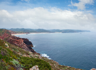 Fototapeta premium Summer Atlantic rocky coast misty view with sandy beach (Costa Vicentina, Algarve, Portugal).
