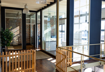 Empty, sunny office corridor and glass walled meeting room, copy space