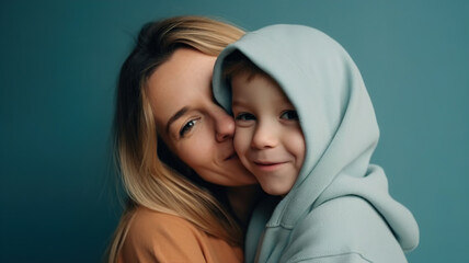 Happy Mother's Day Close-Up Portrait of Mother and Son Child Hugging with Beaming Smiles on Blue Studio Background