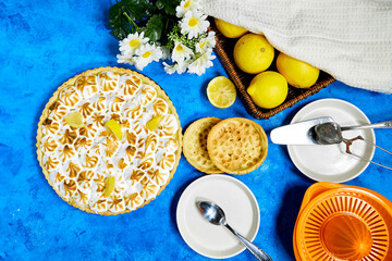 Traditional french lemon Meringue tart with fruits and orange juicer with daisy flowers  on blue grunge  background