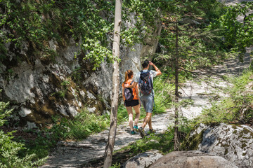 Obraz premium Two young hikers with backpacks, a couple in love exploring nature
