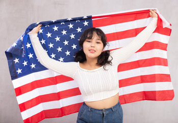 Portrait of smiling young asian girl in casual clothes holding USA flag in studio
