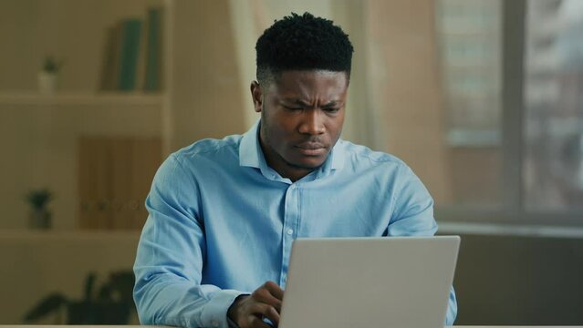 Upset stressed African American man ethnic sad businessman working laptop in home office frustrated angry worker entrepreneur broker lost internet on computer business project failure job bankruptcy