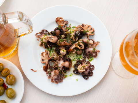 Ready to serve baby octopus with greens on plate