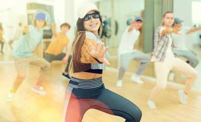 Group of positive teenagers dancing modern hip-hop dance in studio.