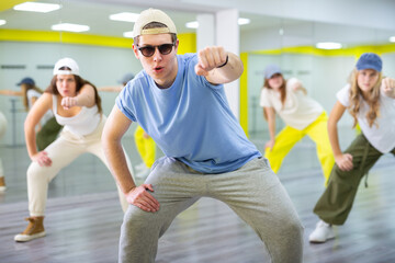 Flexible and energetic male and female teenage dancers having fun during dance lesson together in spacious hall