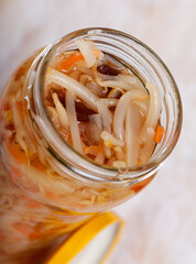 Exotic Chinese salad - vegetarian appetizer of pickled bean sprouts, white cabbage, carrot, bell pepper and corn cobs in glass jar..