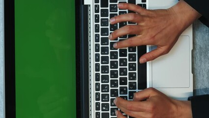 Woman working on laptop computer with green screen. Vertical video - Powered by Adobe