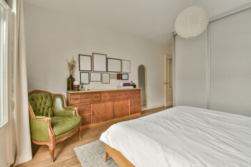 a bedroom with a bed, chair and mirror on the wall next to an open door that leads to another room