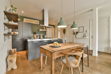 a kitchen and dining area in a small apartment with wood flooring, white walls and light green pendants on the ceiling