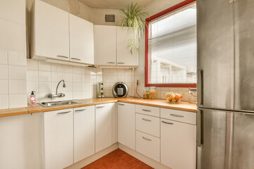 Fototapeta premium a small kitchen with white cabinets and red trim around the counters, including an orange rug on the floor