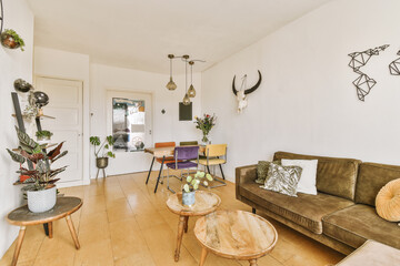 a living room with couches, tables and plants on the wall in front of the door to the kitchen