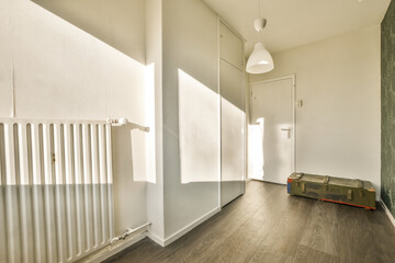 a room with wood flooring and white walls, including a radiac heater on the right side