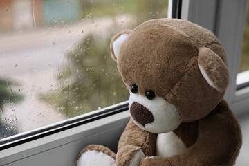 Cute lonely teddy bear on windowsill indoors, closeup. Space for text