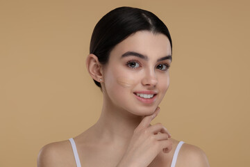 Teenage girl with swatch of foundation on face against beige background