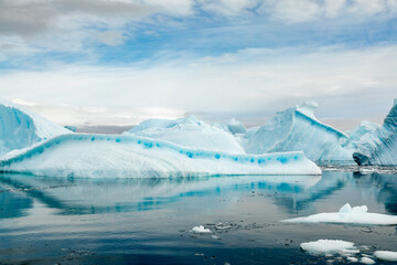 Turquoise, Blue and White Icebergs Relected in Smooth Glassy Water in Antarctica Near Cuverville Island