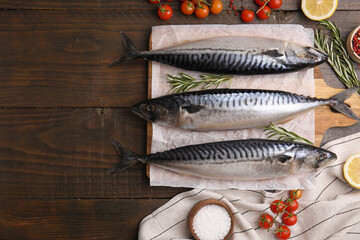 Raw mackerel, tomatoes and rosemary on wooden table, flat lay. Space for text