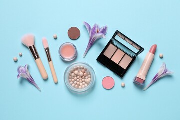 Flat lay composition with different makeup products and beautiful flowers on light blue background