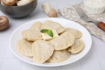 Fototapeta na wymiar Delicious dumplings (varenyky) with tasty filling and butter on white tiled table, closeup