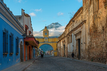 Antigua city and Santa Catalina arch with unrecognizable people before sunrise, Guatemala.