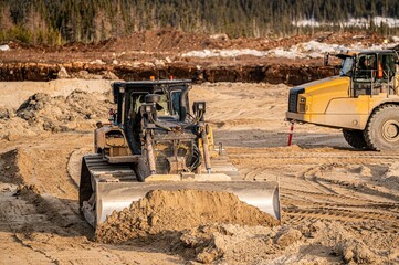 Bulldozer pushing sand on the bottom of an excavation in boreal forest © Larry Dallaire