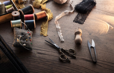 Sewing tools on old desk.Fringe or lace tapes and silk trimmings with gold (brass) scissors on a...