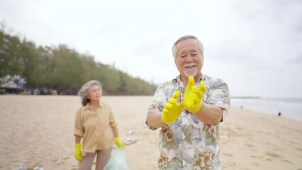 Asian family senior couple travel ocean on summer holiday vacation. Elderly man and woman picking up plastic trash and garbage together on the beach. Environmental conservation waste pollution concept - Powered by Adobe