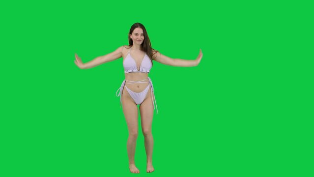 Happy and carefree girl dancing with bikini in front of a green screen chroma key