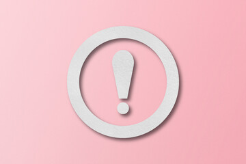 White paper punched into the shape of an exclamation mark. warning sign set on pink paper background