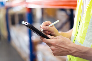 Professional warehouse staff using digital tablet to review the stock inventory on shelf in an import - export warehouse. Senior warehouse worker uses tablet to check an item on rack.