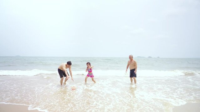 Group of Happy Asian family, Three Generation men and little girl in swimwear have fun outdoor lifestyle playing sea water together at tropical beach during travel ocean on summer holiday vacation.