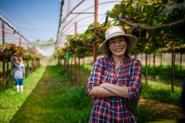 A vineyard woman smiling happy standing with her arms crossed on the farm.