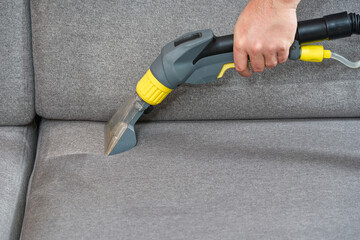 Sofa chemical cleaning with professionally extraction method. Wet textile sofa cleaning. home cleaning service. cleaning sofa with washing suction cleaner closeup.