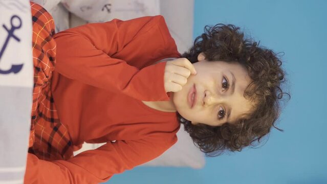 Vertical video of Confused boy muttering to himself in bed.
Boy in pajamas talking to himself in bed at night making plans.
