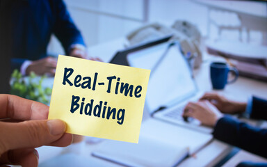 Male hand holding sticky note written Real-Time Bidding.