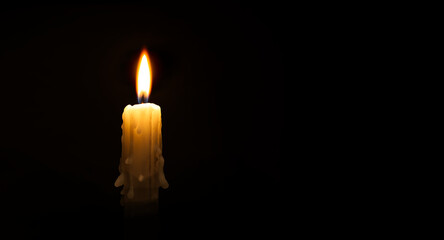 Burning wax candle against a black background