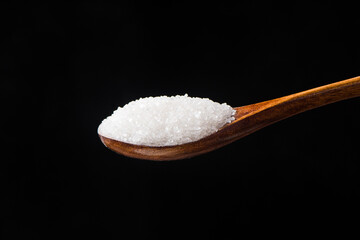sugar in spoon on black background