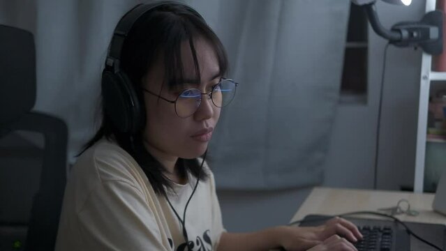 Woman wears headset and glasses, works at computer typing on keyboard